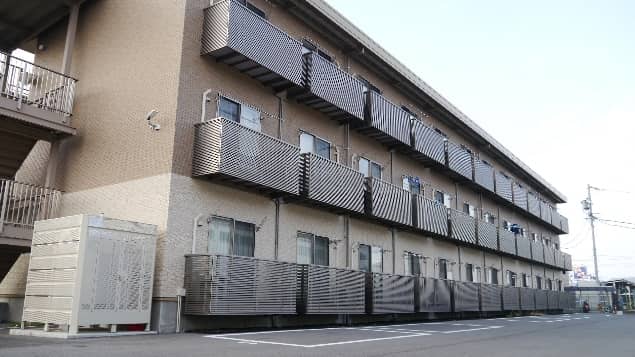 ブラウンとベージュのツートンカラーのマンション(社員寮)を伝える写真
